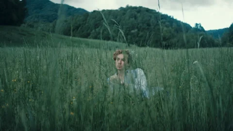 Young person feels alone in a grassy field surrounded by nature's beauty Stock Footage 321552233