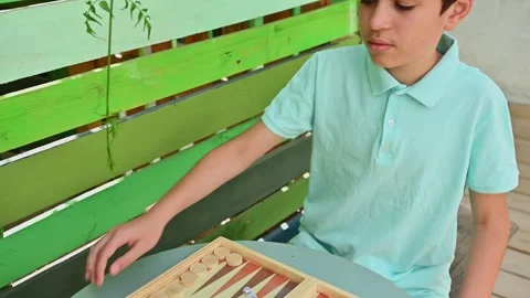 Young person playing backgammon at outdoor table Stockbeeldmateriaal 290053317