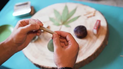 Young person preparing marijuana joint while rolling a pipe Stock Footage 137440627