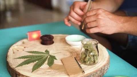 Young person preparing marijuana joint while rolling a pipe Stock Footage 137440632