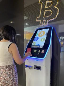 Young person scans QR code from red phone at Bitbase ATM to trade with Stock Photos