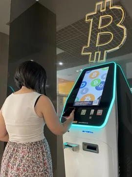Young person scans QR code from red phone at Bitbase ATM to trade with Stock Photos