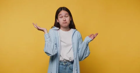 Young person shows confusion while posing against yellow background during .. Stockbeeldmateriaal 328248075