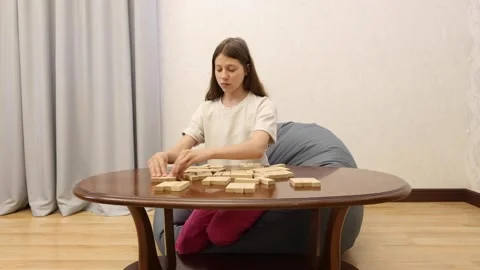 A young person sits at a table, making a move on a chess board Stock Footage 278885868