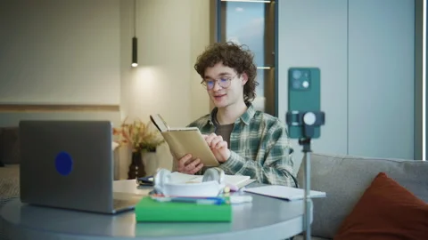 Young person studies at home while using a laptop, smartphone, and notebook Stock Footage 341475154