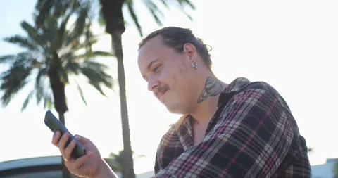 Young Person Using Smartphone Outdoors Near Palm Trees In Bright Sunlight... 库存影片 333525076