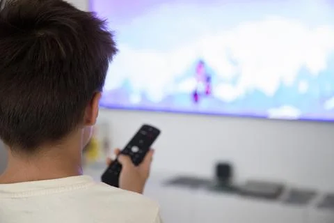 Young person using TV remote to change channels at home Stock Photos