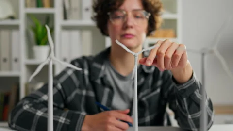 Young person working on miniature wind turbines in a modern workspace during Stock Footage 323717026