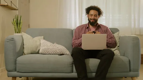 A Young Person is Working Remotely on Their Laptop While Also Using Their Vídeos de archivo 285682403