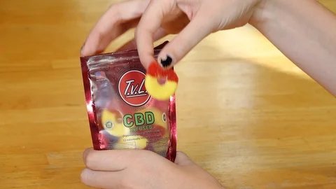Young person's hand taking a CBD infused gummy candy from a bag. Stock Footage 120031183