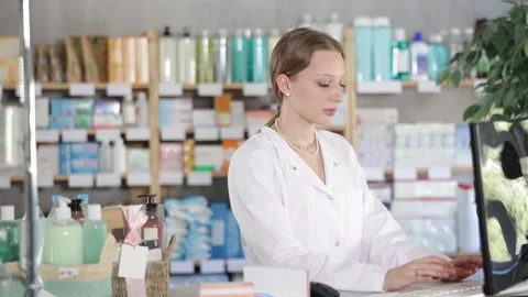 Young pharmacist stands near the computer and checks the availability of goods Stock Footage 341427142