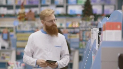 Young pharmacist working in his large pharmacy. Placing medications inventory Stock Footage 126527476