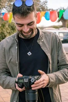 Young photographer smiling while looking at the pictures he has taken with hi Foto stock