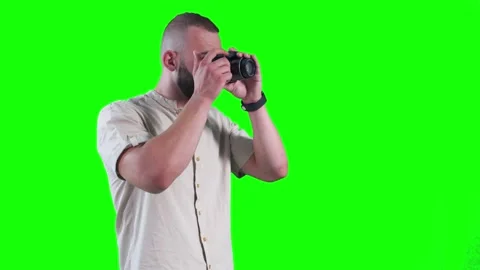 Young photographer using camera and taking photos against green background Stock Footage 136369240