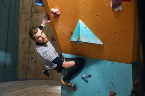 Young physically challenged boulderer hanging at colourful climbing wall Stock Photos
