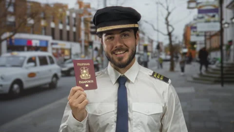 Young pilot man holding a philippine passport stands smiling on a busy city.. Stock Footage 309891029