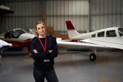 Young pilot posing in the hangar surrounded by airplanes. Stock Photos