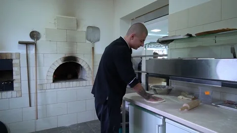 A young pizza maker prepares pizza in the kitchen of the restaurant. The cook Stock Footage 84830647