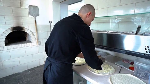 A young pizza maker prepares pizza in the kitchen of the restaurant. The cook Video stock 84830843