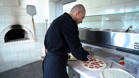 A young pizza maker prepares pizza in the kitchen of the restaurant. The cook Video stock 84830938