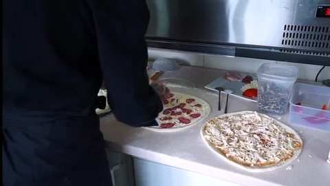 A young pizza maker prepares pizza in the kitchen of the restaurant. The cook Stock Footage 84830957