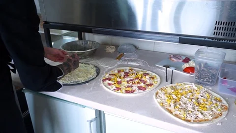 A young pizza maker prepares pizza in the kitchen of the restaurant. Prepares Video stock 84831002