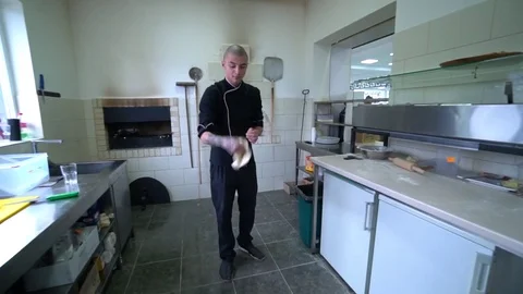A young pizza maker prepares pizza in the kitchen of the restaurant. The cook Video stock 84832148