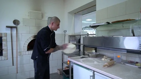 A young pizza maker prepares pizza in the kitchen of the restaurant. The cook Stock Footage 84832473