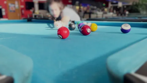 Young Player Striking Pool Balls on Blue Felt Table in Indoor Billiards Hall Stock Footage 340004746