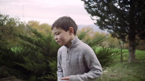 Young playful boy throwing a bright orange into the air as he's walking around a Stock Footage 199461540