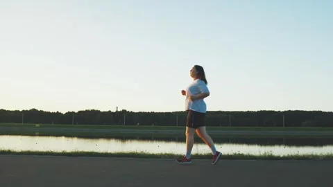 Young plump brunette overweight plus size woman jogging for weight loss. Weight Stock Footage 282372449
