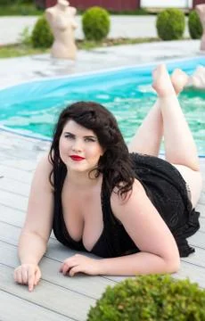 Young plus size model lying near the outdoors pool Stock Photos