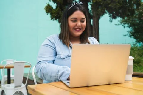 Young plus size woman using laptop at coffee shop. Stock Photos
