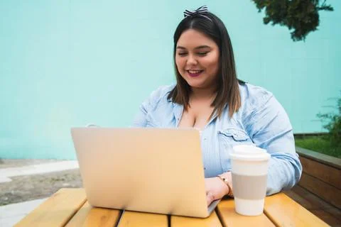 Young plus size woman using laptop at coffee shop. Stock Photos
