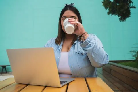 Young plus size woman using laptop at coffee shop. Stock Photos
