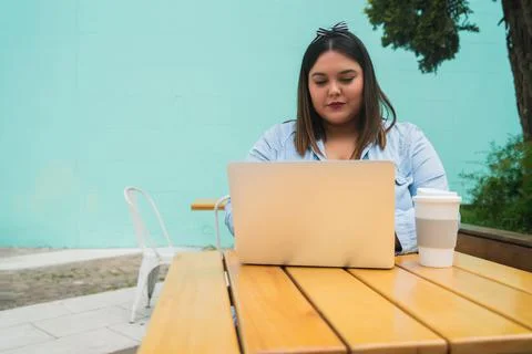 Young plus size woman using laptop at coffee shop. Stock Photos