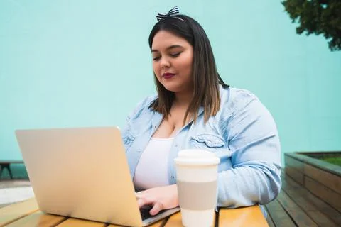 Young plus size woman using laptop at coffee shop. Stock Photos