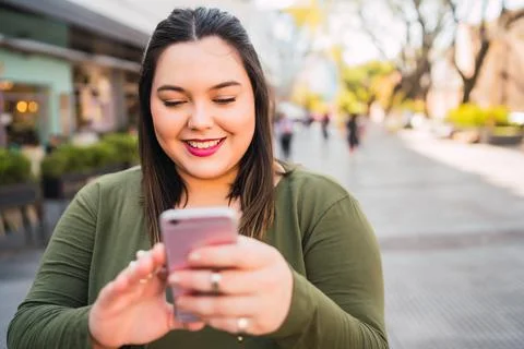 Young plus size woman using her mobile phone. Stock Photos