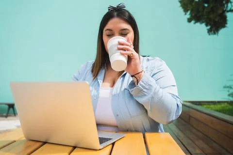 Young plus size woman using laptop at coffee shop. Stock Photos