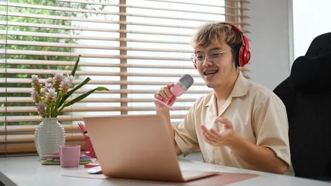 Young podcaster using a microphone and laptop computer recording audio for Foto stock