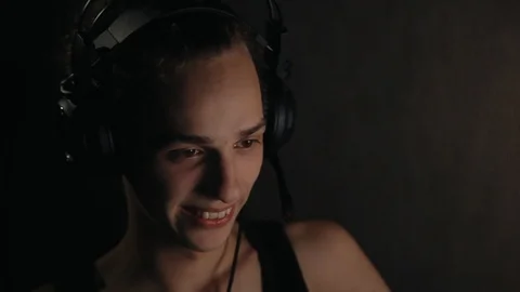 Young positive gamer in headpsones using computer at home at night Видео 99051093