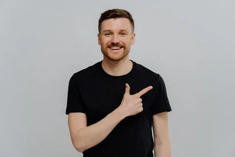 Young positive man pointing at upper right corner with pleased face expression Foto stock