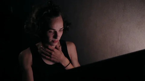 Young positive man sitting in front of computer at home in dark room Video stock 99051067