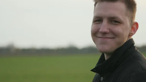 Young positive man standing back to camera turns to it. Smiling man's face in 库存影片 106315951