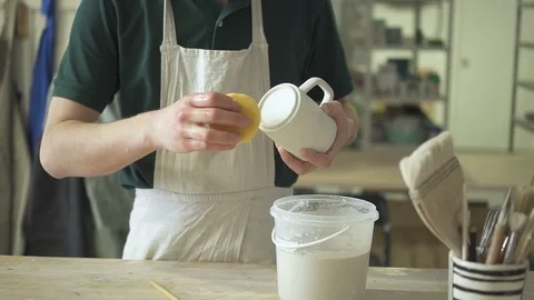 Young potter is cleaning mug while standing at table in pottery workshop. Stock Footage 90131672