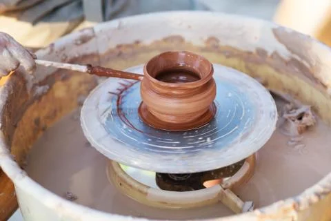 Young potter, creating an earthen jar on the circle, close-up Stock Photos