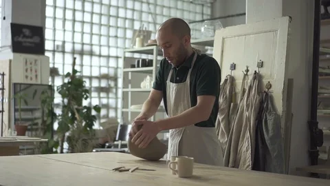 Young potter is kneading clay on table in pottery workshop. Video stock 87324571