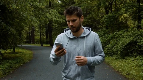 Young powerfull runner outside in autumn nature park with phone Stock Footage 79242138