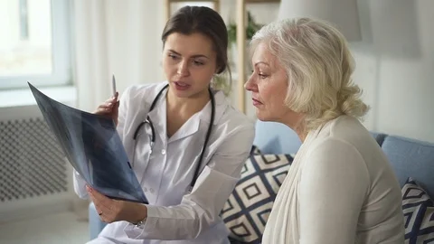 Young practitioner doctor talking with old woman about her X-ray Stock Footage 103715948