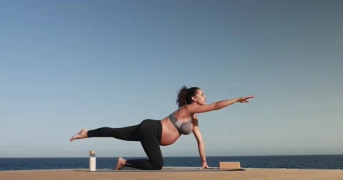 Young pregnant woman doing yoga on the beach - Maternity and